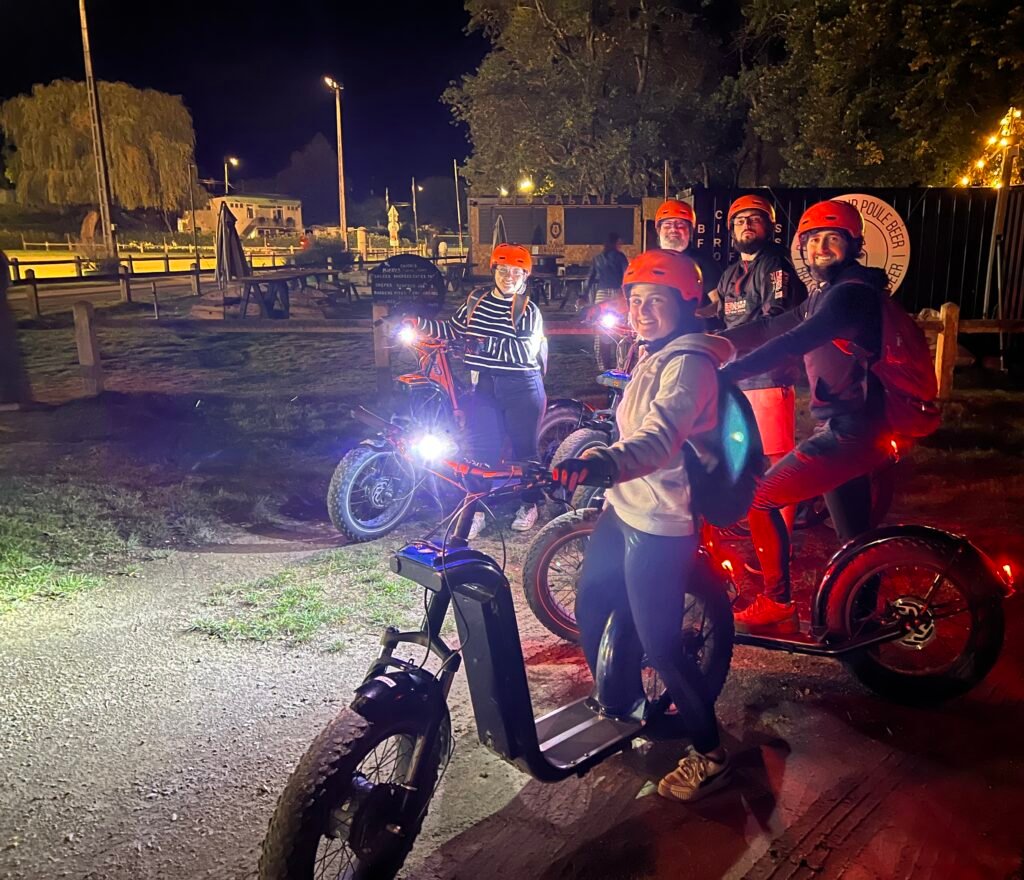 Groupe en trottinette électrique de nuit avec éclairage, balade crépusculaire