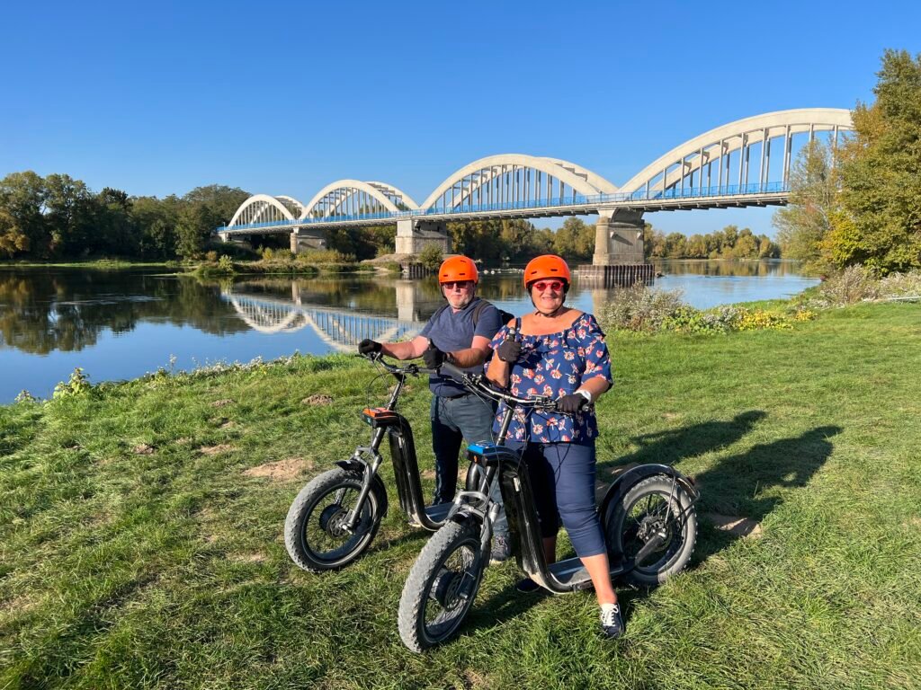 Couple en trottinette électrique devant un pont sur la Loire