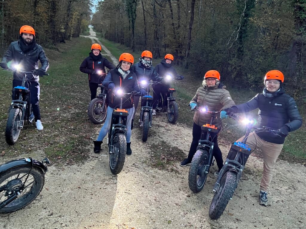 Groupe en trottinette électrique sur un sentier forestier à la tombée du jour