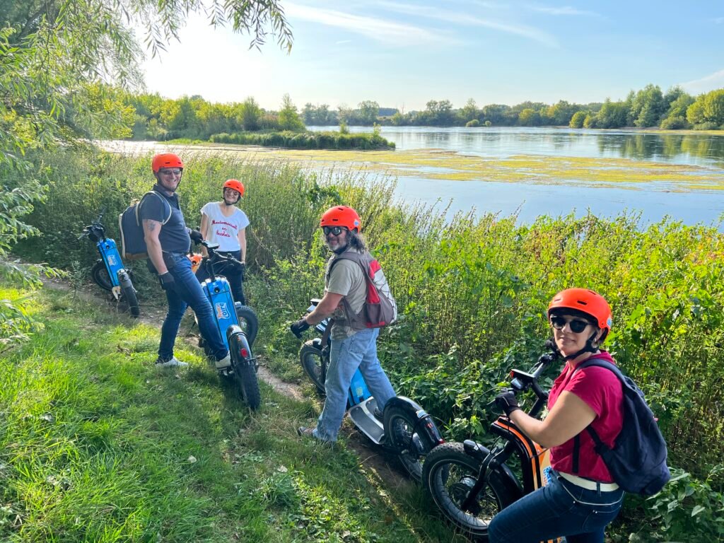Groupe en trottinette électrique au bord de la Loire entre les herbes hautes